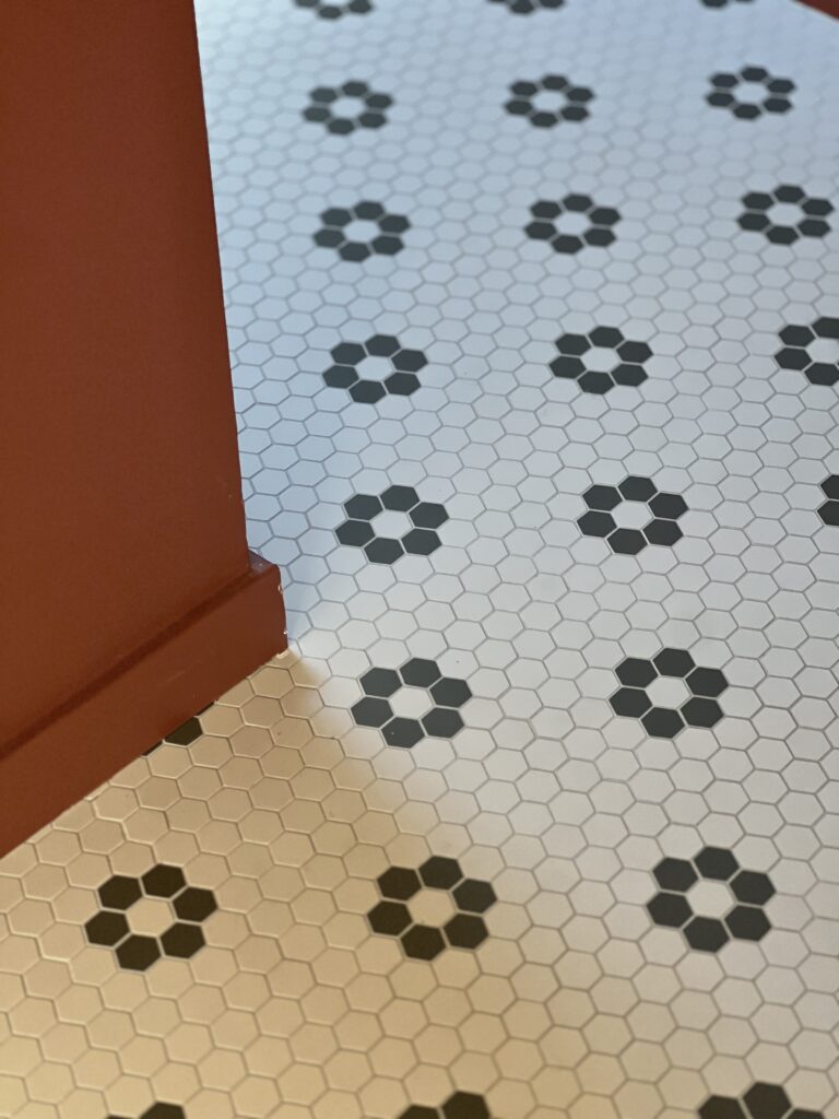 salle de bain rouge cerise effet mat avec carrelage blanc à fleurs noires